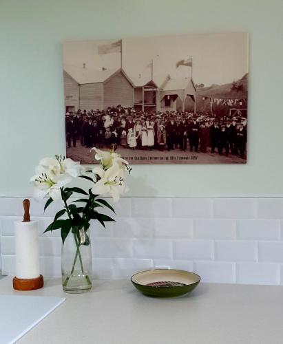 a vase of white flowers and a bowl on a table at The Old Dairy Factory in Norsewood