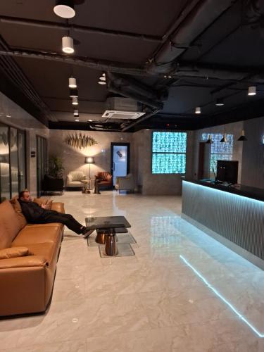 une personne assise sur un canapé dans le hall dans l'établissement NBG beach panorama apartment batumi, à Batoumi