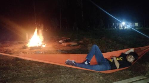 a person laying on a hammock in front of a fire at Quinta las Marias, Ecolodge, camping y Tiny wood house in Guateque