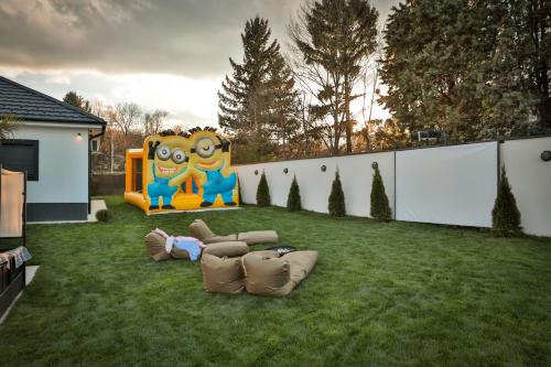 a child laying on the grass next to a playground at The Crown Pool Villa in Belgrade