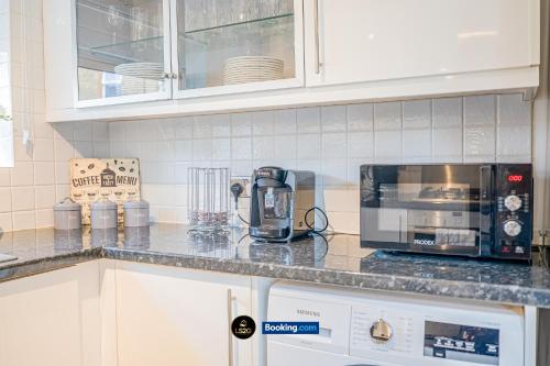 a kitchen counter with a coffee maker and a microwave at Spacious 5-Bed House with Parking in Wood Green by LS2G Stays in London