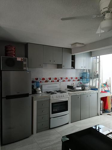 a kitchen with white appliances and a large window at Balnearios, Casa villas la palma in Jojutla de Juárez