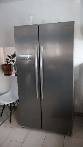 a stainless steel refrigerator in a kitchen with a table at VILA RAISA in Neagra Şarului