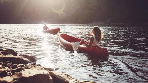 a woman is sitting in a canoe in the water at Blue Basecamp - Adventure Starts Here! in Shaver Lake