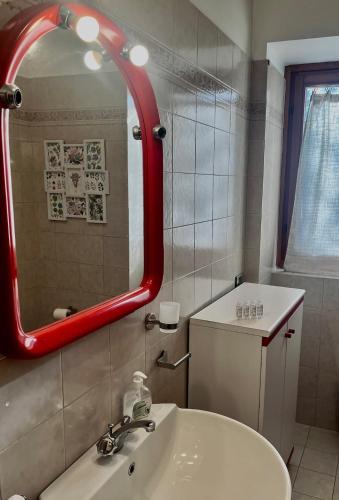 a bathroom with a sink and a red mirror at Appartamento sul Lago con Terrazza Panoramica in Riva di Solto