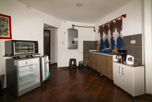 a room with a kitchen with a microwave and a tv at El Triunfo Apart - Departamentos Equipados Potrero de los Funes in Potrero de los Funes