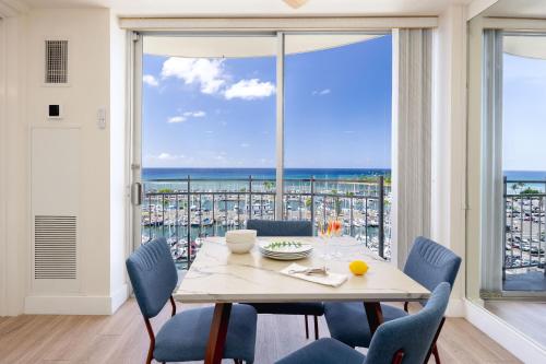 a dining room with a table and chairs and a large window at Ilikai Marina Stunning Ocean & Harbor Views - Walk to the Beach! in Honolulu