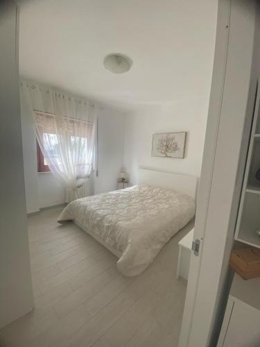 a white bedroom with a bed and a window at A due passi dalla spiaggia in Vieste