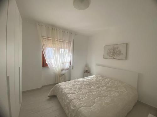 a white bedroom with a bed and a window at A due passi dalla spiaggia in Vieste