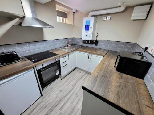 a kitchen with white cabinets and a wooden counter top at Comfortable Stay - Loughborough in Nottingham