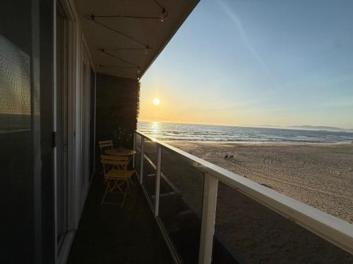 a balcony with a view of the beach at sunset at Oceanfront 2 BR w Pool & Parking 234 in Hermosa Beach