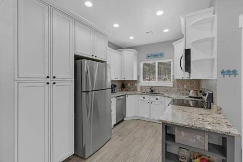a kitchen with white cabinets and a stainless steel refrigerator at Large Flagstaff Home with Guest House in Flagstaff