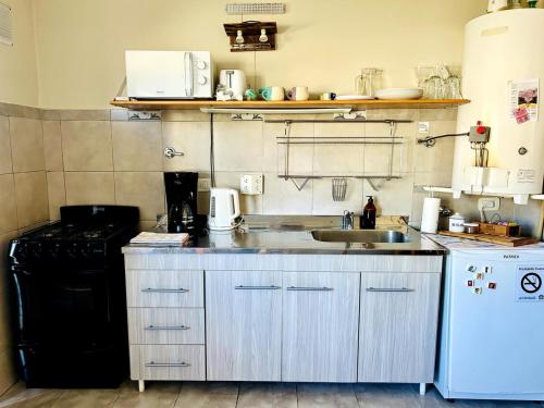 a small kitchen with a sink and a stove at Casita del centro Esquel luz natural, wifi alto, ideal parejas, check in autónomo in Esquel