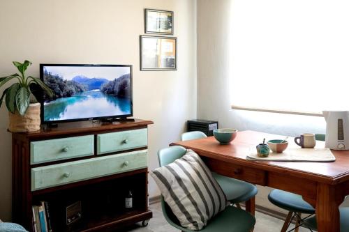 a living room with a desk and a tv on a dresser at Casita del centro Esquel luz natural, wifi alto, ideal parejas, check in autónomo in Esquel