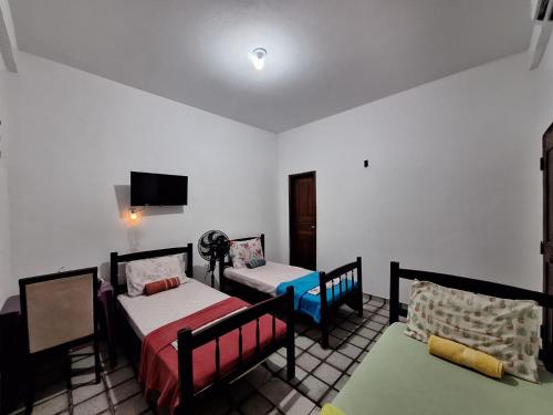 a room with two beds and a tv on the wall at Suíte perto do Centro e de Praias in São Luís