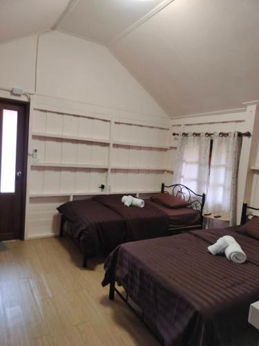 a bedroom with two beds and a window at สวรรค์บ้านนา คาเฟ่ ณ บ้านนา in Pakha