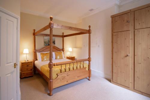 a bedroom with a wooden canopy bed in a room at Newton House Hotel in Alstonfield