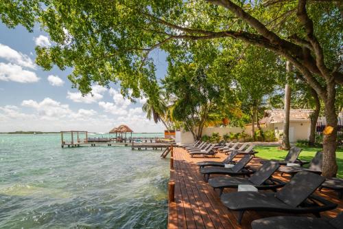 a row of lounge chairs on a dock in the water at Casa Aakal Lagoon Front in Bacalar