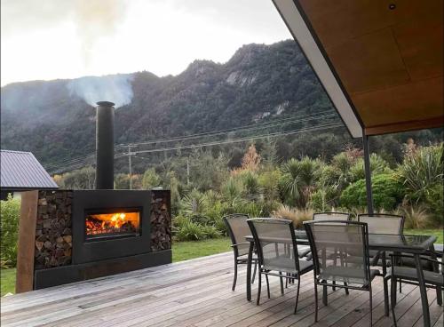a fireplace on a deck with a table and chairs at Bobs Cove Nature Getaway and spa in Mount Creighton