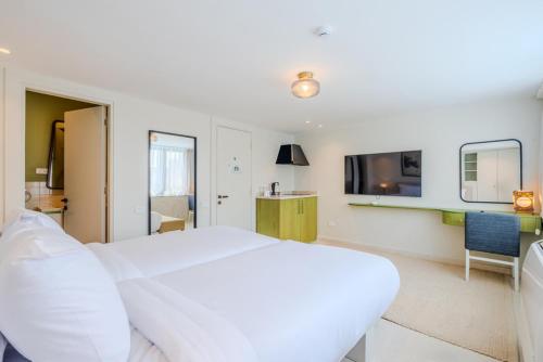 a bedroom with a large white bed and a tv at Longchamps l Zamalek l Boutique Hotel with Breakfast in Cairo