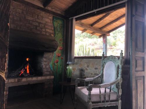 a room with a fireplace and a chair and a window at Hotel Monteverde Sutatausa in Sutatausa