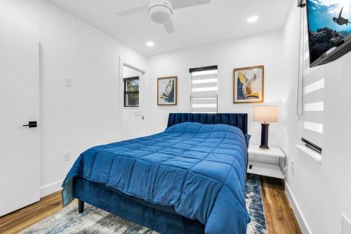 a bedroom with a blue bed in a white room at Modern Home with large private yard - Next to downtown & beach & airport - Pet friendly in Fort Lauderdale