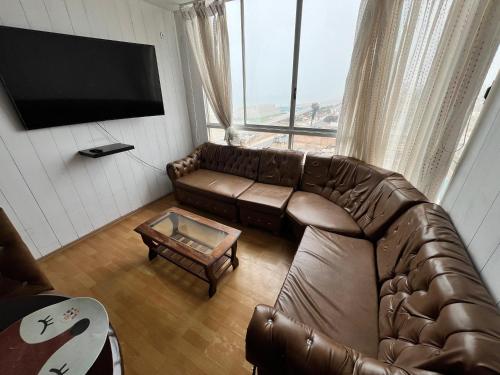 a living room with a brown leather couch and a tv at DEPARTAMENTO FRENTE ARENa 1 in Lima