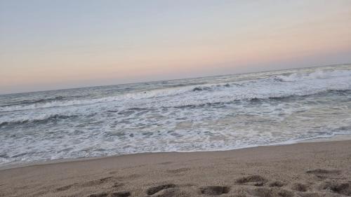 a beach with footprints in the sand and the ocean at Puerto Manglar Hostal in Guachaca