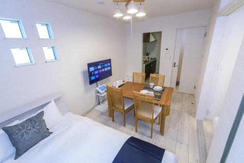 Una habitación con una mesa y un dormitorio con una cama. en Elisabeth Hakata, en Fukuoka