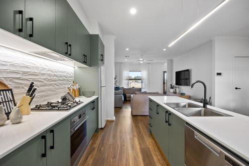 a kitchen with green cabinets and a sink and a living room at Olive Lane at Mount Barker Workspace, Wi-Fi in Mount Barker