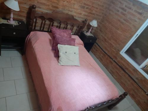 1 dormitorio con 1 cama con sábanas y almohadas rosas en Cabaña ParaLelo 1, en Viedma