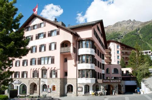 un bâtiment rose avec une montagne en arrière-plan dans l'établissement Hotel Rosatsch, à Pontresina