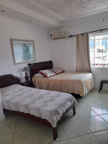 a bedroom with two beds and a window at Martin de Sá - Casa da Olivia in Caraguatatuba
