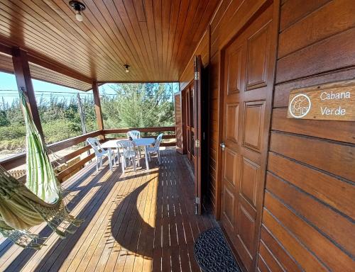a wooden deck with a table and chairs on it at La Tatuira, Cabana Amarela in Pinheira