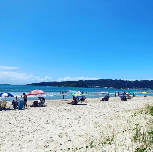 a group of people sitting on a beach with umbrellas at La Tatuira, Cabana Amarela in Pinheira