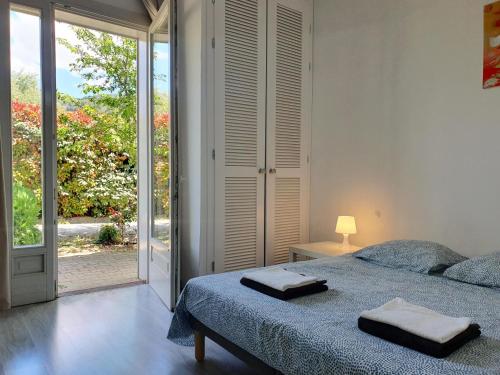 une chambre avec un lit et une porte coulissante en verre dans l'établissement Le Ranch, à Oupia