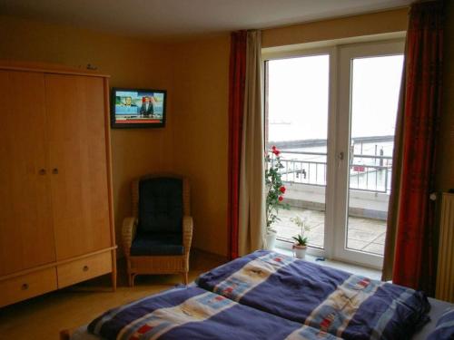 Un dormitorio con una cama y una ventana y una silla. en 1-bedroom apartment, en Cuxhaven