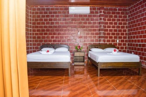 two beds in a room with a brick wall at Saraya Lodge & Camping in Iquitos