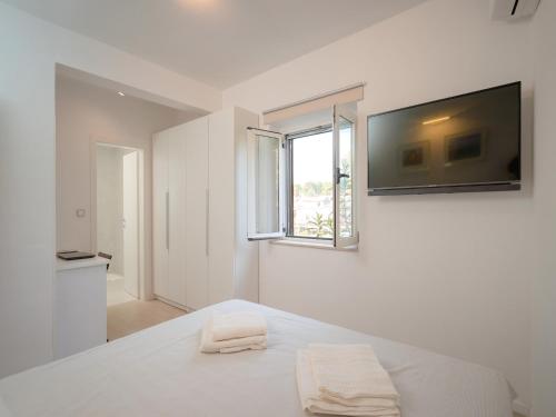 ein weißes Schlafzimmer mit einem Bett und zwei Handtüchern in der Unterkunft Nicely decorated house with top roofed terrace in Vrboska