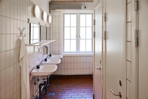 a bathroom with three sinks and a window at Rønne Vandrerhjem in Rønne