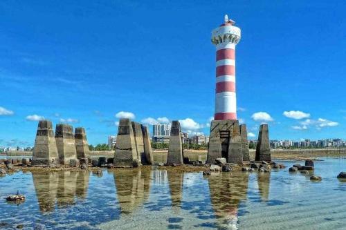 a lighthouse on the shore of a body of water at Smart Stay - Apto 1202 - Ponta Verde Maceió in Maceió