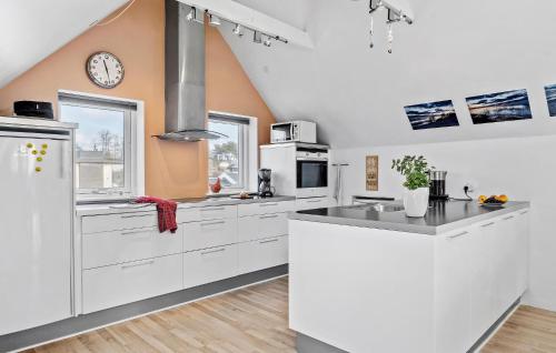 a kitchen with white cabinets and a clock on the wall at Stunning Home In Børkop With Sauna in Børkop