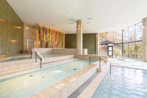 a swimming pool in a building with a large window at Ooedo Onsen Monogatari Premium Yamanaka Grand Hotel in Kaga