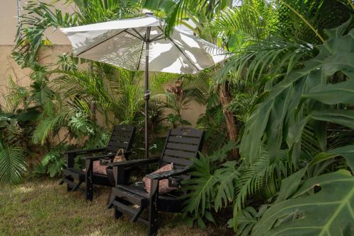 two chairs and an umbrella in a garden at Bohemian Bliss Villa with Private Pool & Concierge 1A in Tulum