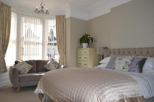 Un dormitorio con una cama y un sofá y una ventana. en The Westbourne Guest House, en Llandudno