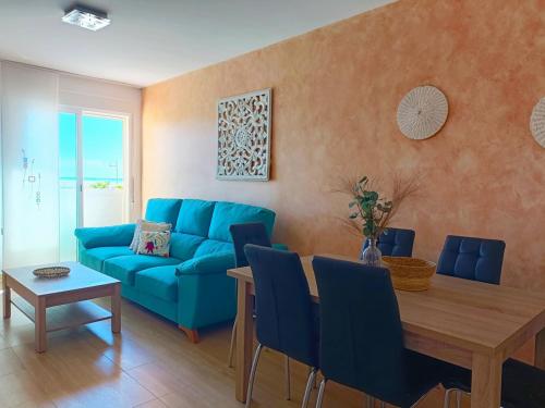 a living room with a blue couch and a table at Cala Grande suites 3 hab, vistas al mar y terraza in El Cabo de Gata