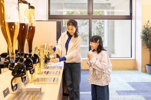 a woman and a little girl looking at wine bottles at Ooedo Onsen Monogatari Premium Yamanaka Grand Hotel in Kaga