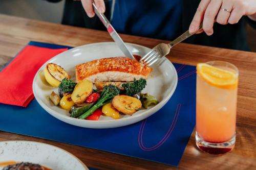 a bowl of fish and vegetables and a glass of orange juice at Courtyard by Marriott Brno in Brno