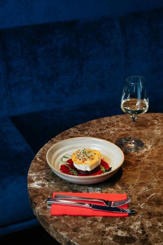 a table with a plate of food and a glass of wine at Courtyard by Marriott Brno in Brno