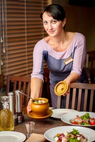 a woman standing at a table with a bowl of food at Kolobok in Luts'k